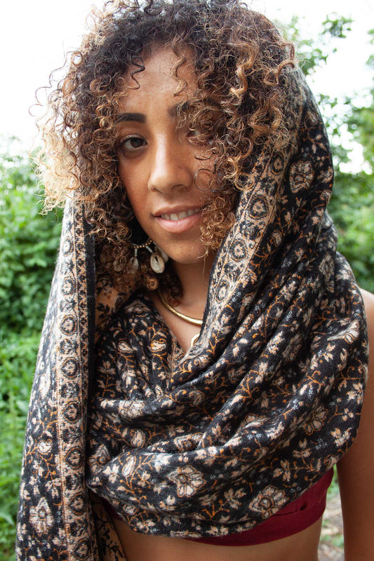 Black Floral (charcoal and bronze paisley print) oversize yak wool shawl draped as a wrap around the shoulders.