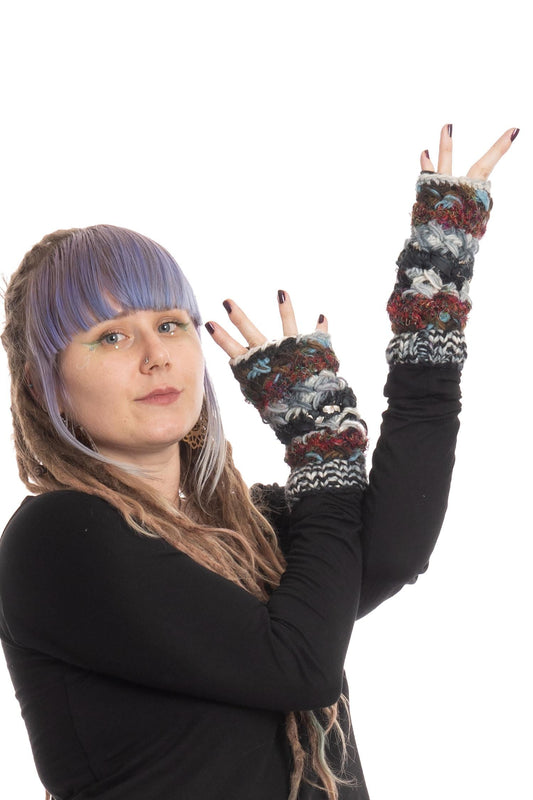 Black upcycled wool armwarmers with woven sari fabric in red, blue and cream patterns and fleece lining, styled as fingerless gloves on a model wearing a black long-sleeve top.