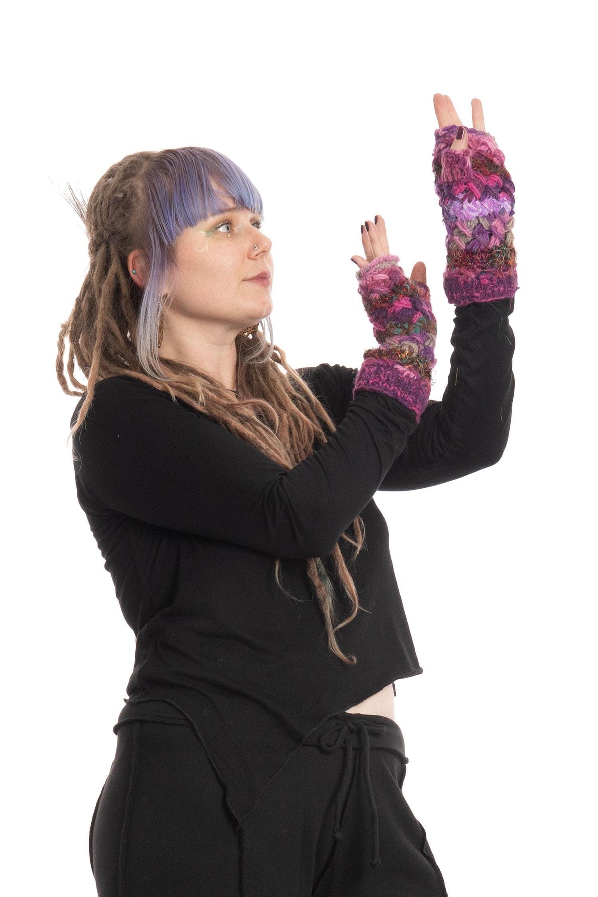 Pink upcycled wool armwarmers with woven sari fabric details and fleece lining, displayed as fingerless gloves worn with a black long-sleeve top.