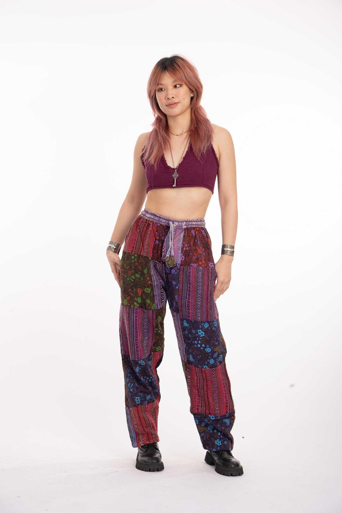 Paarse patchwork joggers met paddenstoelenprint, elastische taille en enkels, gestyled met een kastanjebruine cropped top en zwarte plateaulaarzen.